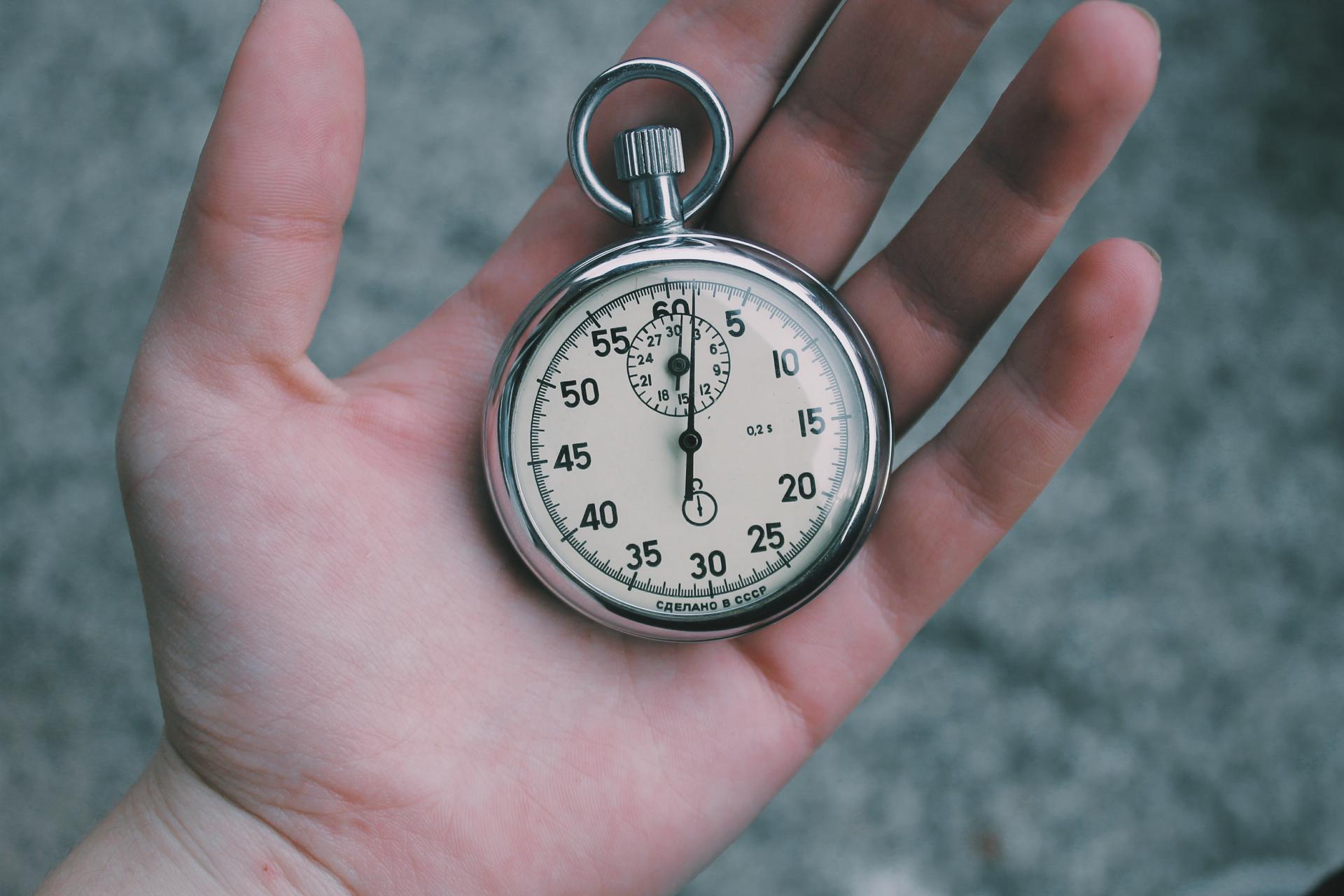 Hand holding an analog stopwatch