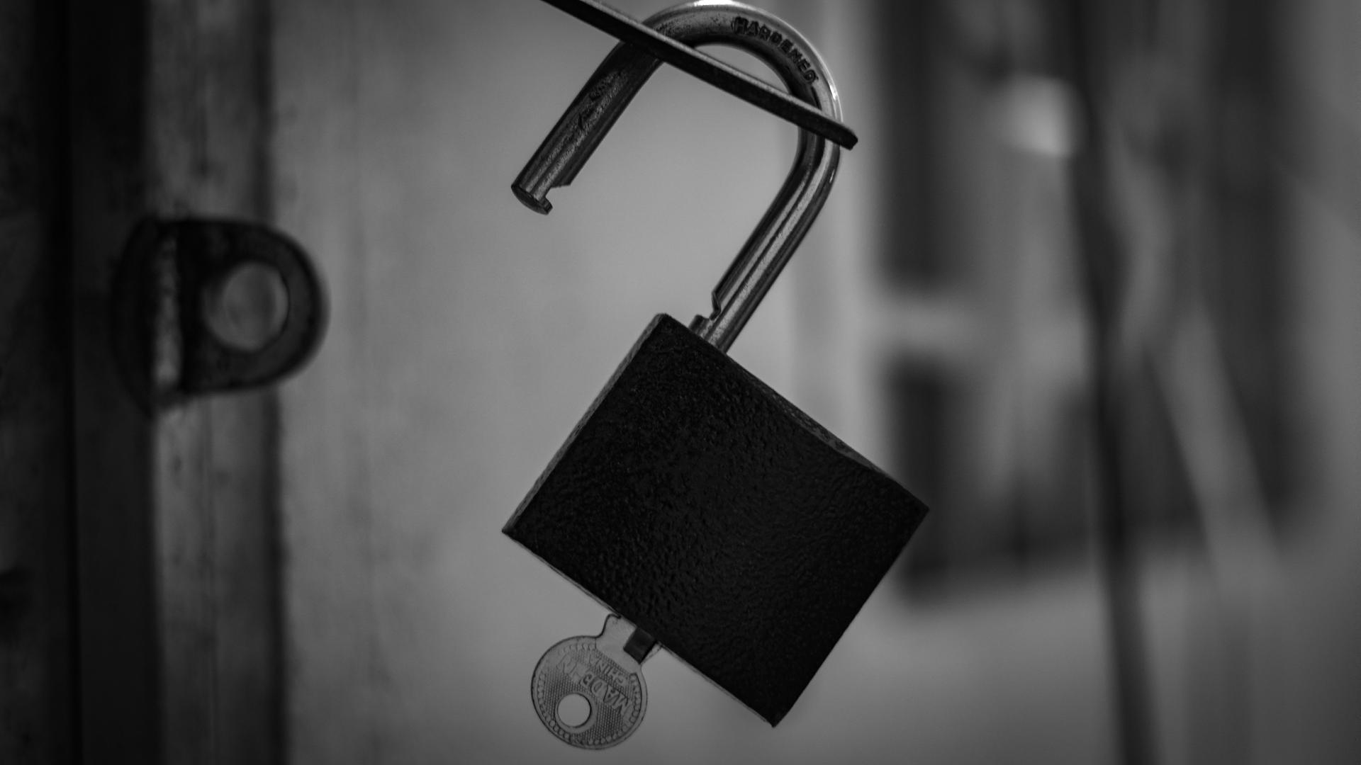 An open lock with its key attached to it.