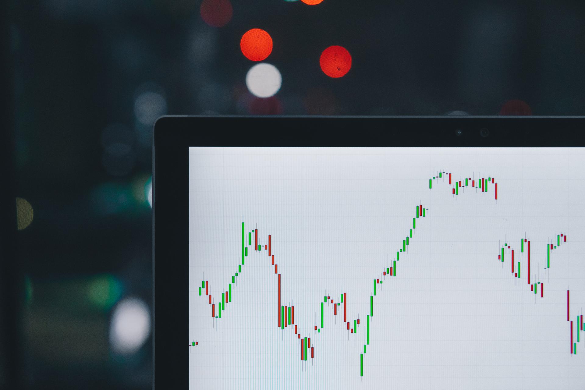 A photograph of a laptop displaying candle charts of stock market data